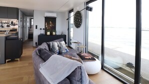 A modern living room with a sofa, a coffee table, and a view of the sea through large windows. - Houseboat With Sauna and Fantastic View (Offingawier)