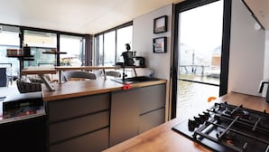 A modern kitchen with a wooden countertop, a gas stove, and a view of the water outside. - Houseboat With Sauna and Fantastic View (Offingawier)