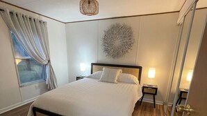 Une chambre à coucher moderne avec un grand lit, un plancher en bois, un élément décoratif mural et une fenêtre avec des rideaux.