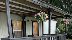 Une véranda couverte avec une balustrade en bois, une petite table et des chaises.
