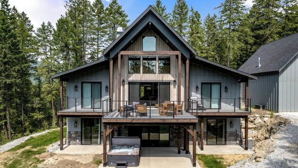 A modern two-story house with a large deck, a hot tub, and a stone fireplace. - Extraordinary Idaho Club Retreat w/ Hot Tub (Sandpoint)