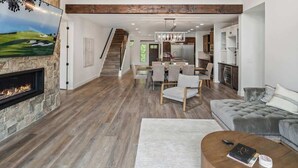 A spacious living area with a fireplace, a dining table, and a sofa. - Extraordinary Idaho Club Retreat w/ Hot Tub (Sandpoint)