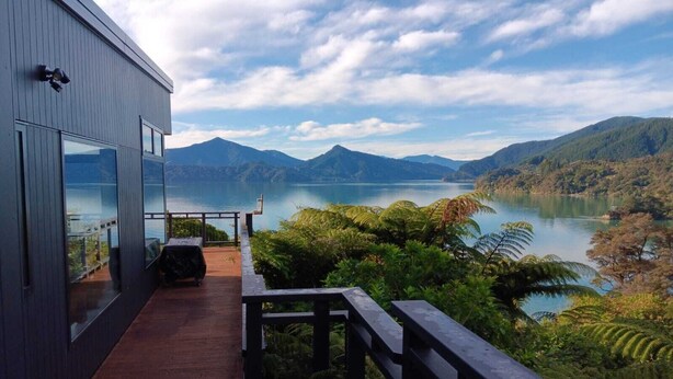 A modern building with a balcony overlooking a lake and mountains.
