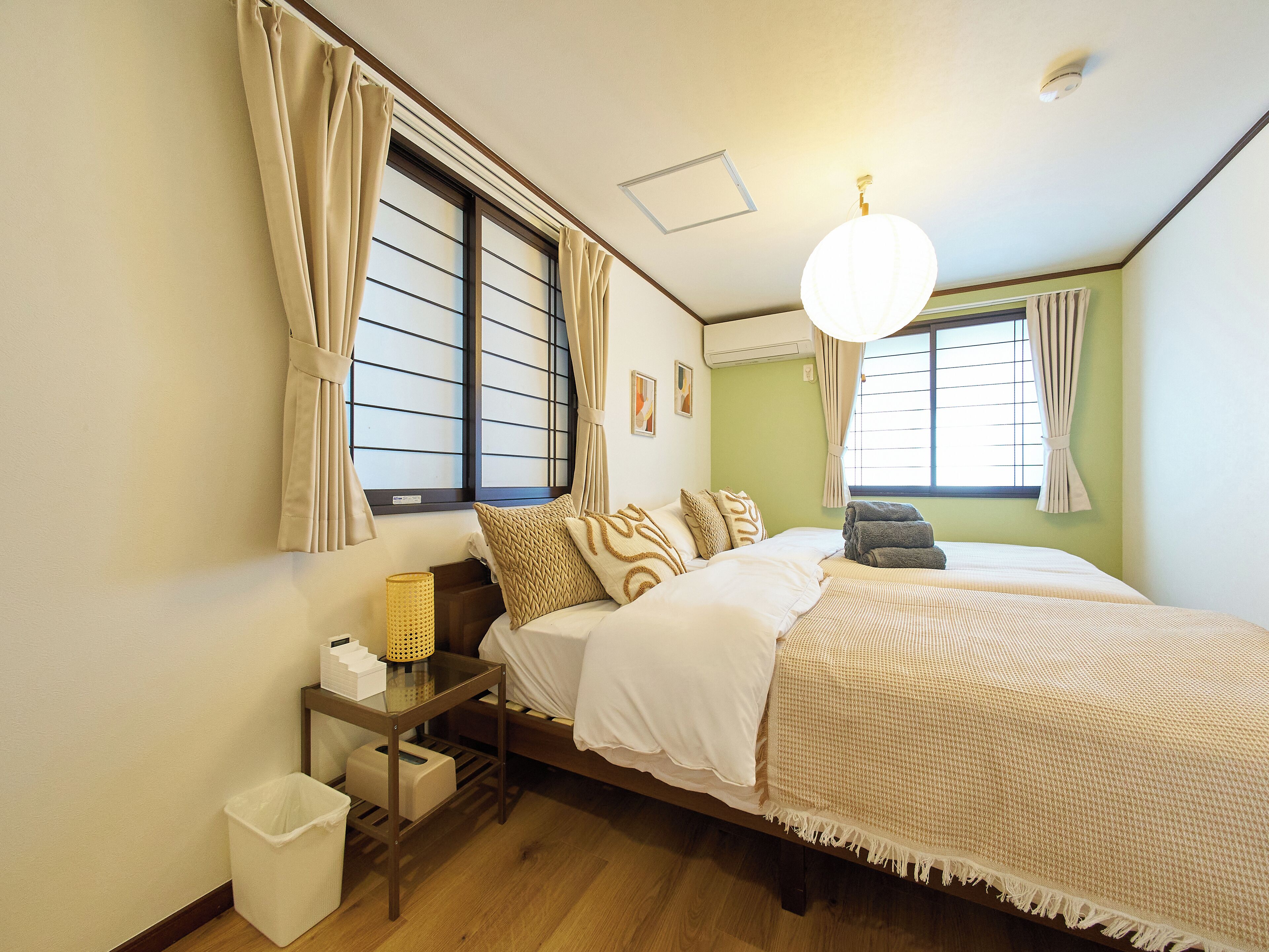 A neatly arranged bedroom with a bed, bedside table, and a small trash bin.