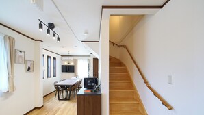 A modern interior with a wooden staircase, a dining area with a table and chairs, and a kitchen area with a TV and appliances. - The Prime TOKYO SKYTREE (Tokyo)