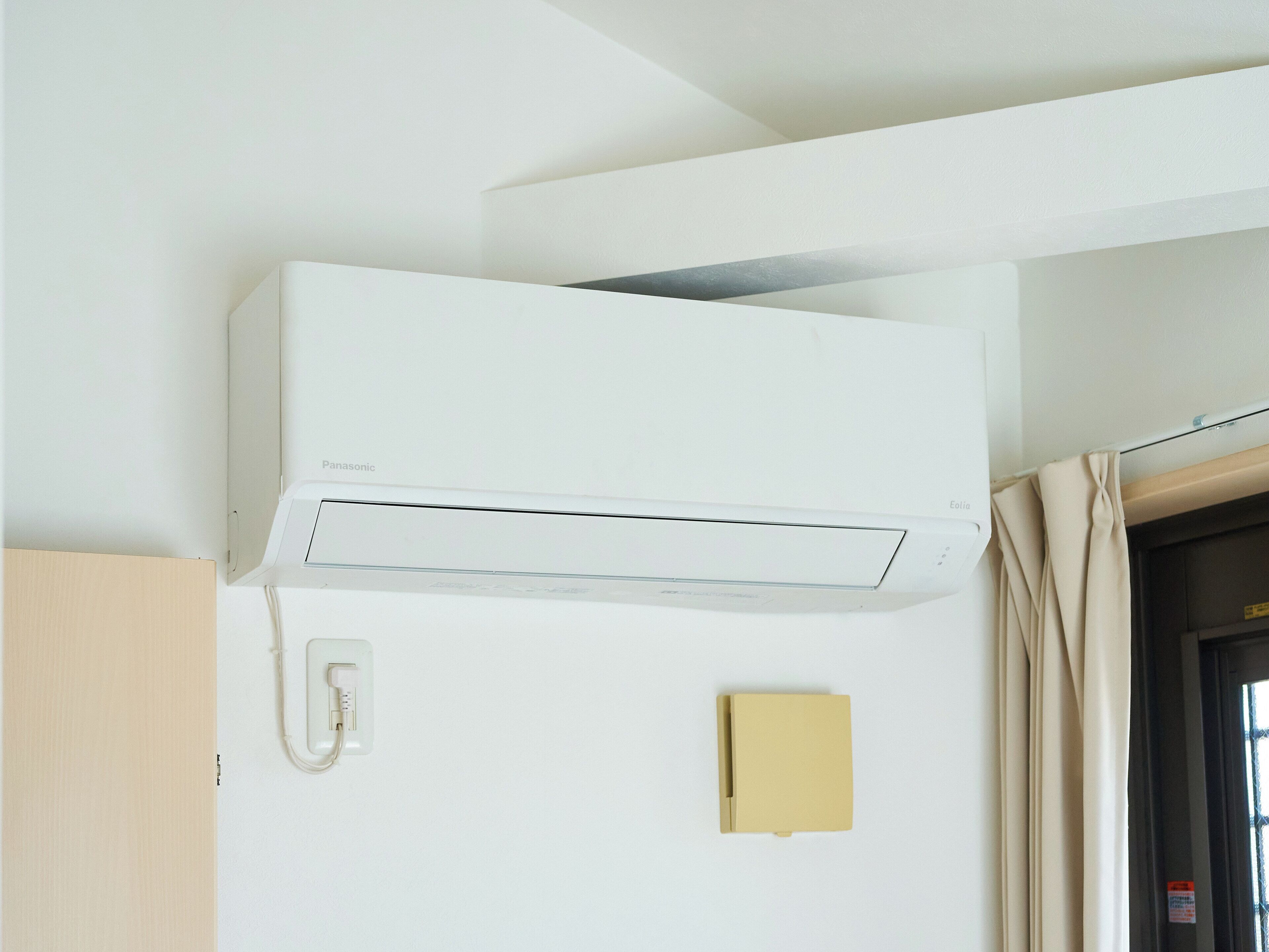 A white air conditioning unit mounted on a wall, a telephone, and a small yellow object.
