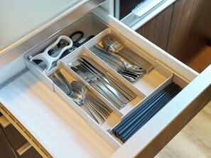 Un cassetto con posate ordinatamente organizzate, tra cui forchette, coltelli e forbici.