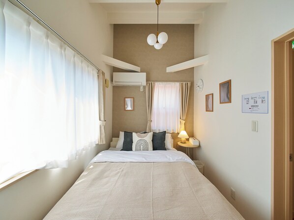 Un dormitorio ordenado con cama, mesitas de noche, lámpara y un reloj en la pared.