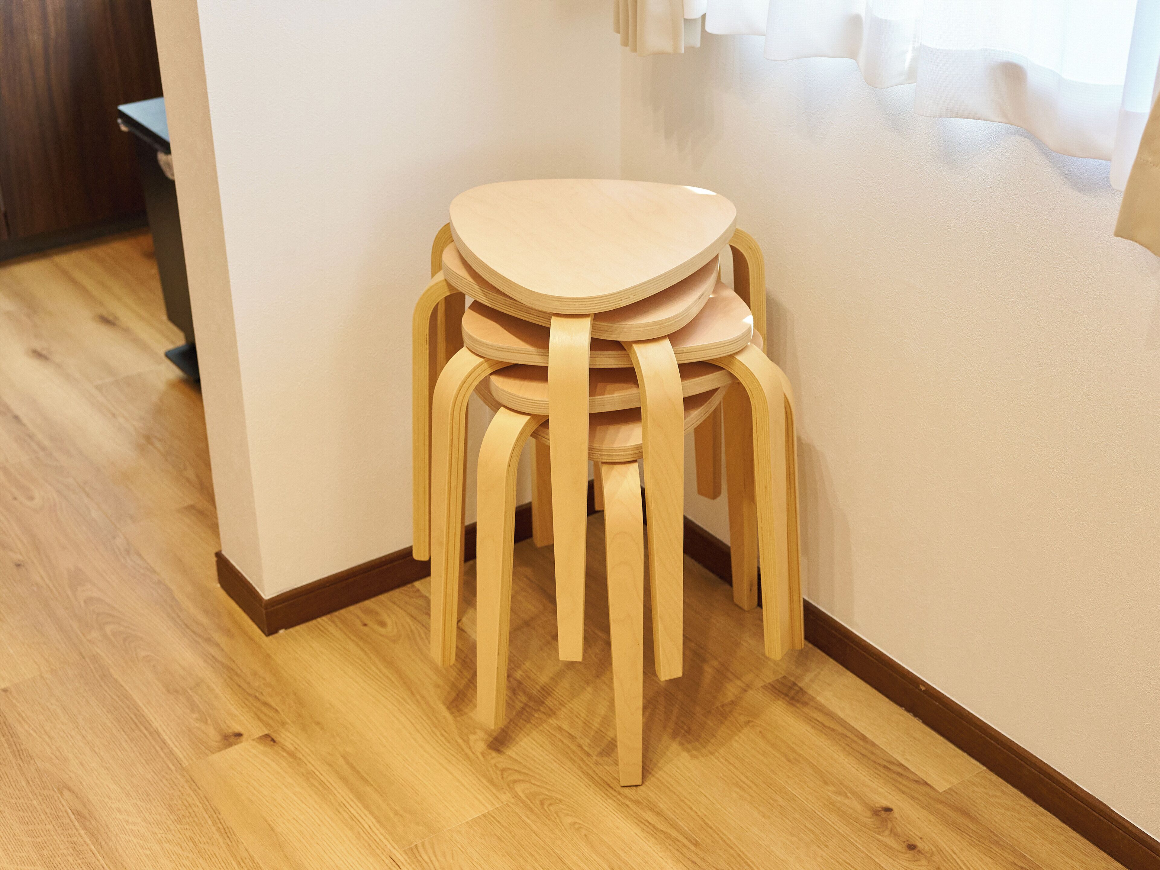Un coin de pièce avec une table et des chaises en bois, un plancher en bois et un mur blanc.