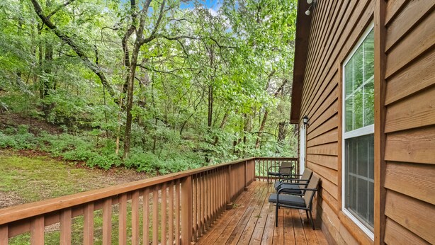 A wooden deck with a railing, overlooking a forested area. - Trailhead Hideaway - bike & breathe! (Bella Vista)