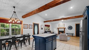 A spacious kitchen with a large island, wooden beams, and a fireplace. - Trailhead Hideaway - bike & breathe! (Bella Vista)