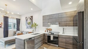 A modern kitchen with a central island, stainless steel appliances, and a minimalist design. - Chic Urban Loft Near Denver w/ Mtn Views (Westminster)