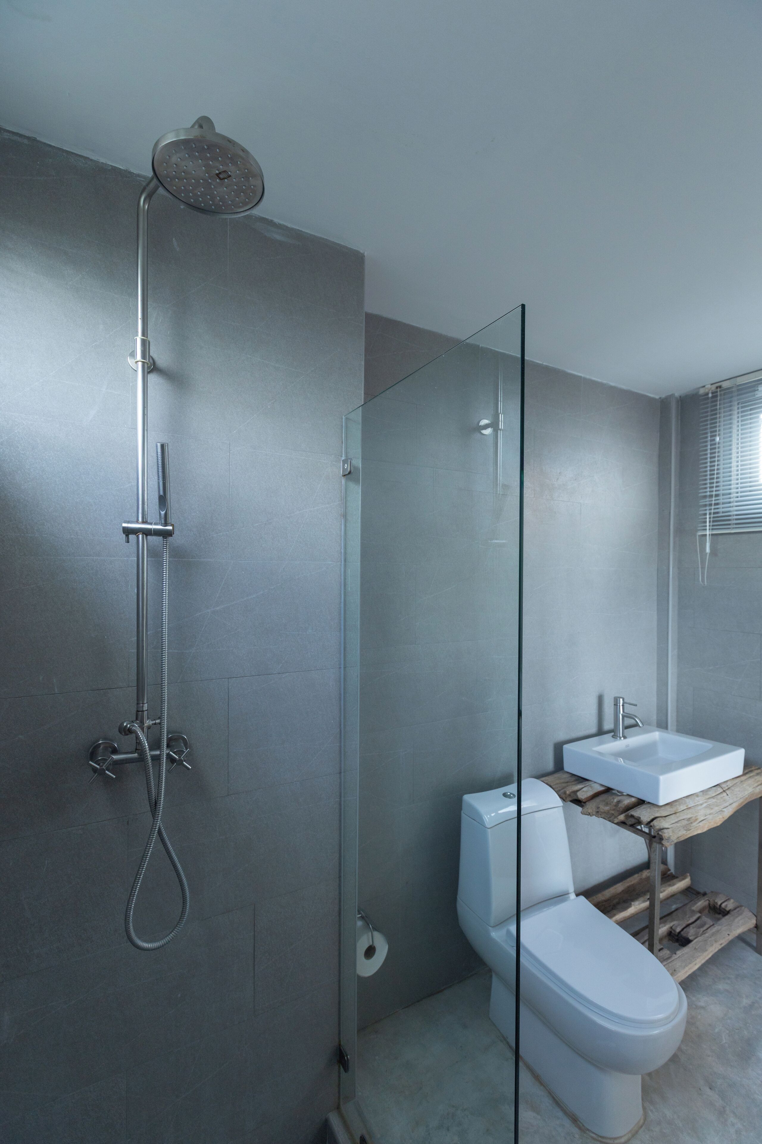 Un baño moderno con ducha de vidrio, inodoro blanco y tocador de madera con lavamanos.
