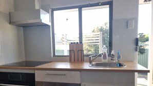 A modern kitchen with a large window, stainless steel appliances, and a wooden countertop. - Relax in a Garden Retreat: Steps to Beaches,Shops,Stations and sdyney CBD. (Miranda)