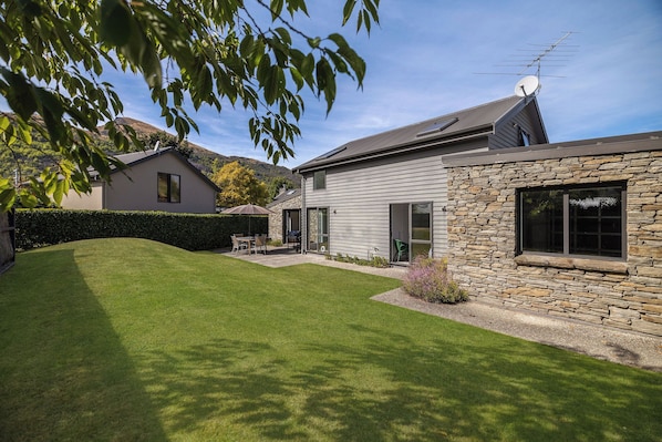 Une maison avec une façade en pierre, une pelouse bien entretenue et une antenne parabolique.