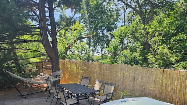 An outdoor patio with a hot tub, wicker chairs, and a table. - Tiny Home Retreat with hot tub (Lake Villa)
