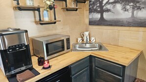 A compact kitchen with a coffee maker, microwave, sink, and a dishwashing unit. - Tiny Home Retreat with hot tub (Lake Villa)