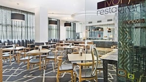 Interior de restaurante con diseño moderno, destacando un muro con textura, varias zonas de estar y un separador de vidrio con el nombre del restaurante.