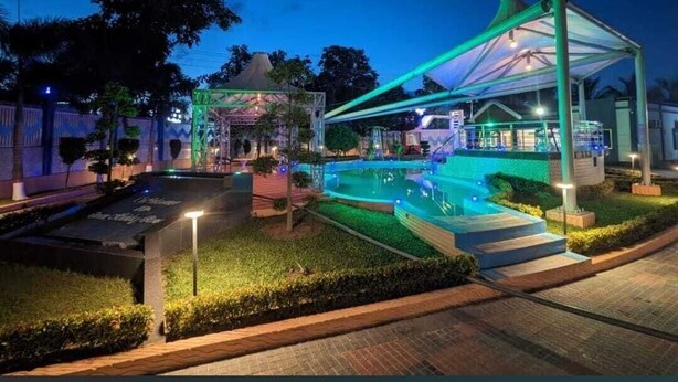 Une vue nocturne d’un hôtel doté d’une piscine, d’un espace extérieur couvert et d’une entrée bien éclairée.