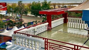Une terrasse avec vue sur la plage, une balustrade rouge et blanche et un ciel dégagé.