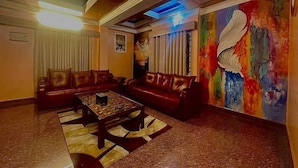 Une pièce comprenant un ensemble de canapés en cuir marron, une table basse et un tableau abstrait aux couleurs vives accroché au mur.