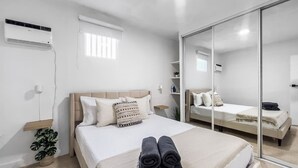 A modern hotel room with a large bed, a bedside table, a mirror, and a potted plant. - Centric Modern Boho Apt For 6 @ San Juan (San Juan)