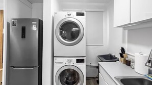 A compact kitchen with a built-in washer and dryer, a refrigerator, a sink, and a countertop with kitchen utensils. - Centric Modern Boho Apt For 6 @ San Juan (San Juan)