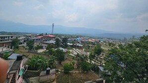 A residential area with houses, a water tower, and distant mountains. - Hotel Anshdeep Palace (Jogindarnagar)