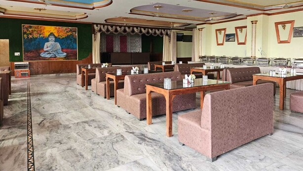 A restaurant with marble flooring, multiple dining tables, and booths. - Hotel Anshdeep Palace (Jogindarnagar)