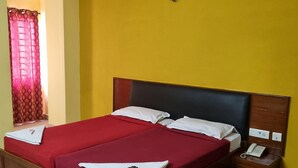 A double bed with red bedding, a wooden headboard, and a bedside table with a phone. - SEA SHELL PARK  (Chennai)