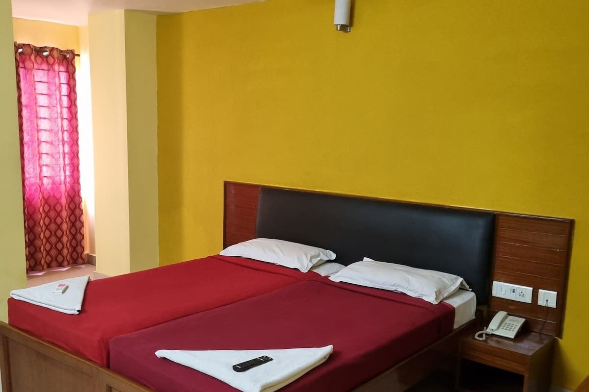 A double bed with red bedding, a wooden headboard, and a bedside table with a phone.