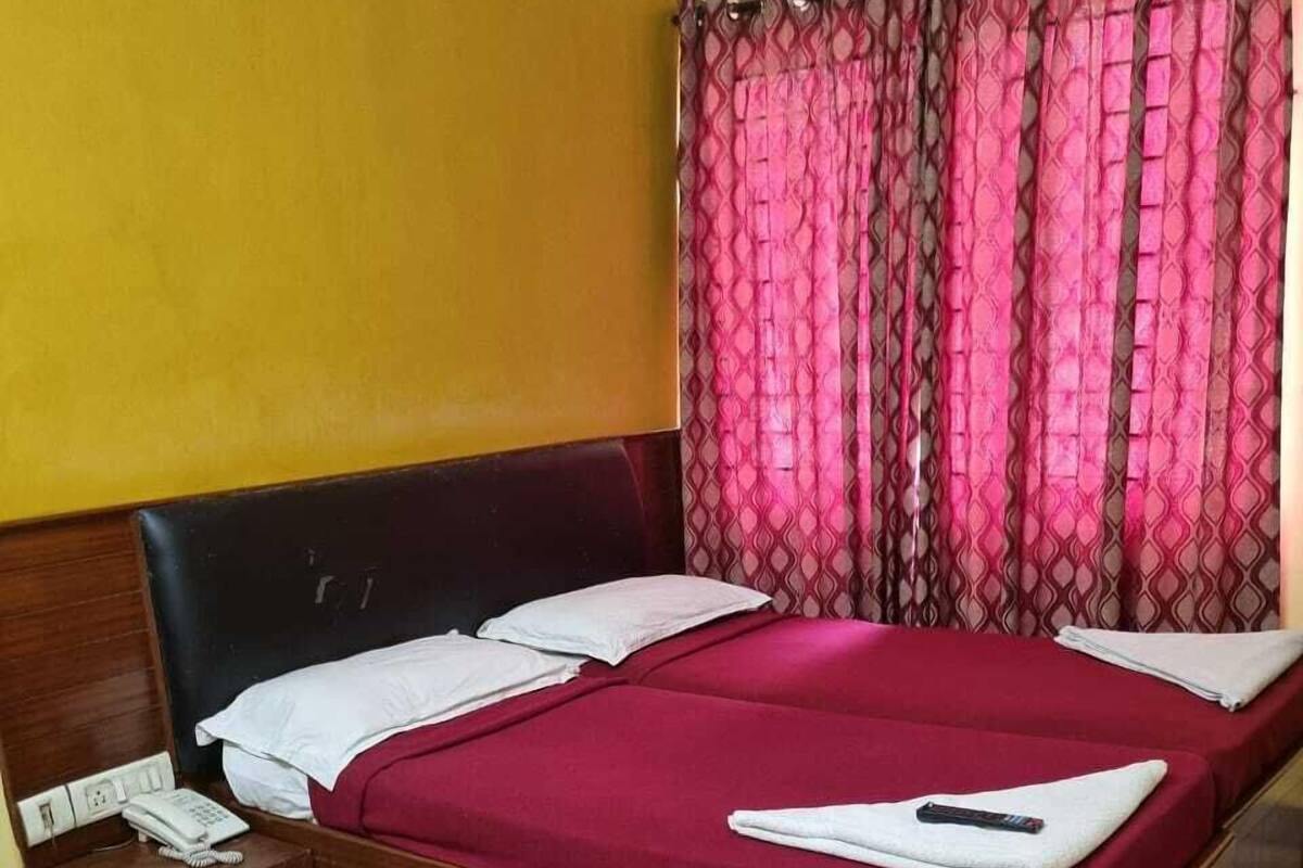 A single bed with a wooden headboard, a bedside table with a phone, and a chair.