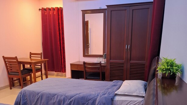 A hotel room with two beds, a desk, a chair, a wardrobe, and an air conditioning unit. - SEA SHELL PARK  (Chennai)