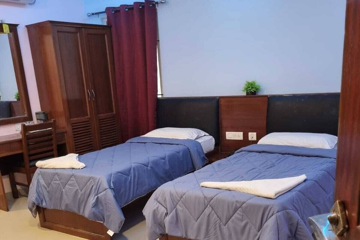 A hotel room with two beds, a desk, and a wardrobe.