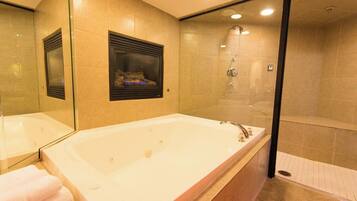 Un baño moderno con una bañera grande, un box de ducha de vidrio y un espejo con estante integrado.