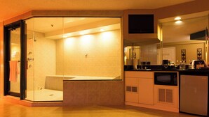 A modern bathroom with a glass-enclosed shower, a vanity with a sink, and a built-in microwave. - Essence Suites (Orland Park)