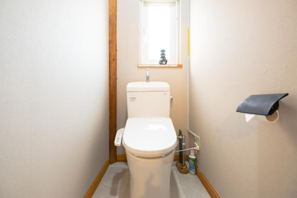 Un baño pequeño y funcional con inodoro, lavamanos y una ventana sobre el lavabo.