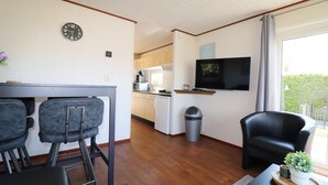 A compact living space with a kitchen, dining area, and a seating area with a TV. - Chalet in Friesland Near Wadden Sea & Franeker (Tzummarum)