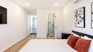 Un dormitorio moderno con una cama grande, una mesita de noche y un televisor montado en la pared.