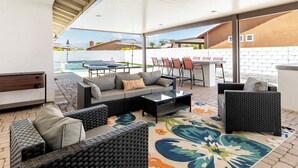 Un patio al aire libre con mobiliario de mimbre, una piscina y vistas a las montañas.