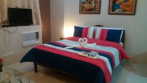 A neatly made bed with a striped bedspread, a pair of white towels, and a small decorative item on the bed.