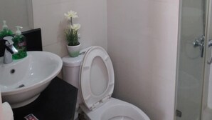 A bathroom with a white sink, toilet, and glass shower enclosure.