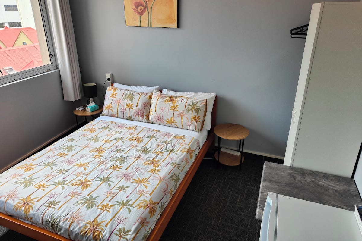 Une chambre d’hôtel avec un lit, une petite table de chevet, une lampe et un tableau au mur.