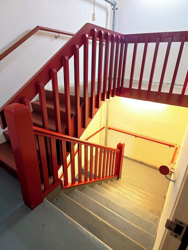 Una escalera con barandillas rojas y una barandilla metálica.