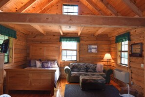 A log cabin interior with a loft bed, a sofa, a chair, and a table. - Butterfly Nook | Pondside Cabin Near Laurel River Lake & Cumberland Falls (Corbin)