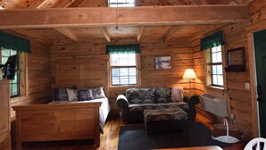 Een blokhut interieur met een bed, bank en tafel.