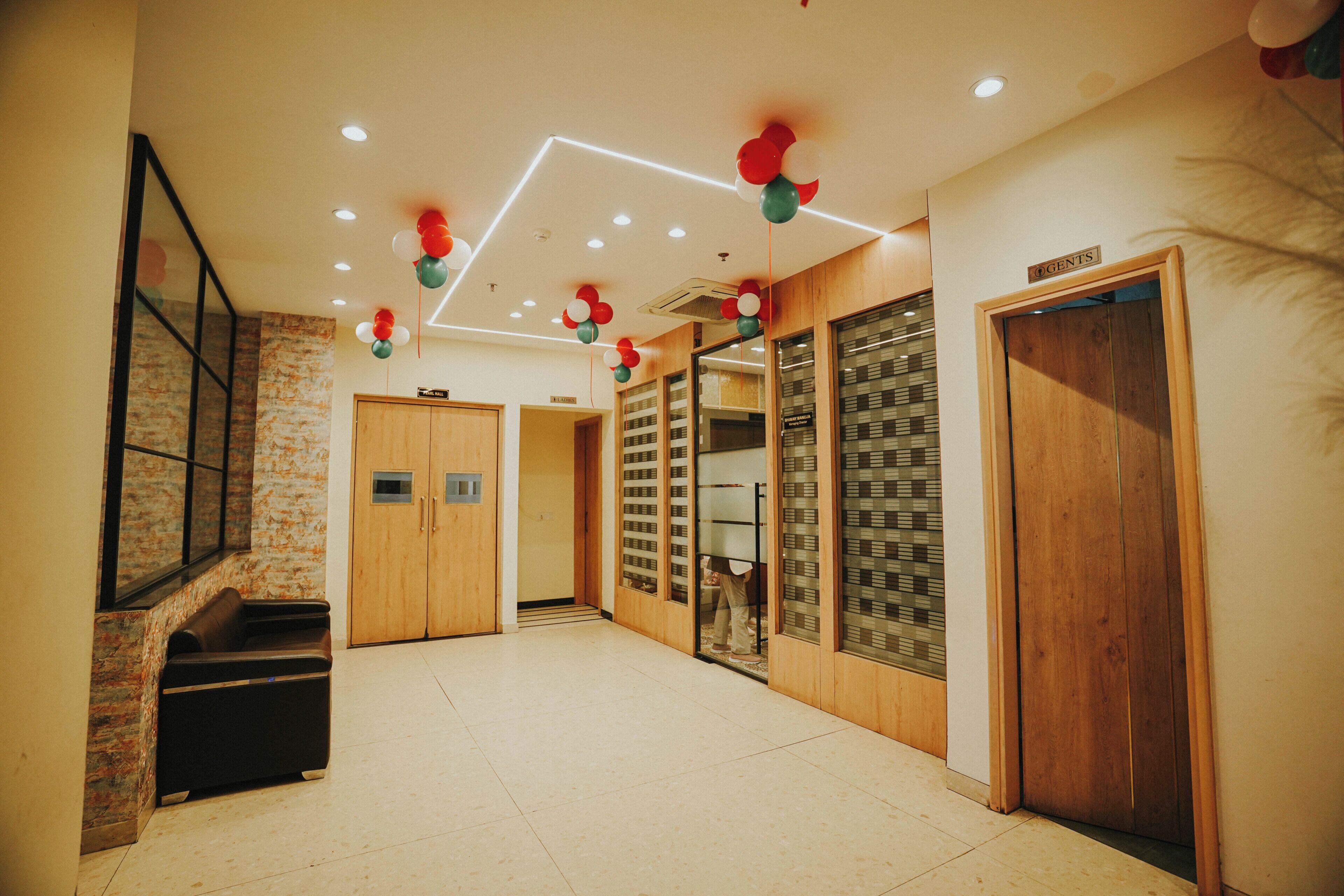 A hotel lobby with a wooden reception desk, a seating area, and a staircase.