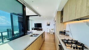 Une cuisine moderne dotée d’un grand îlot central, d’une cuisinière à gaz et offrant une vue sur l’océan.