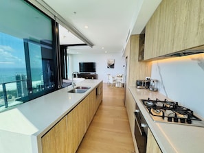A modern kitchen with a large island, a gas stove, and a view of the ocean.