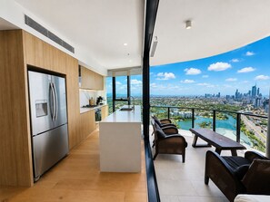 A modern kitchen with a stainless steel refrigerator, wooden cabinets, and a large window overlooking a cityscape. - “Dream View” @ The Star - Panoramic Ocean, City  - 2 bed - Sleeps 5 - Broadbeach (Broadbeach)
